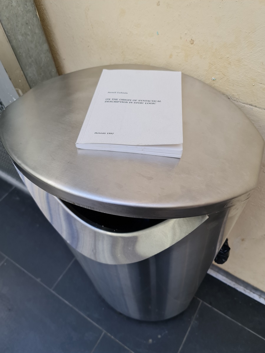 Public trash bin with a copy of Anneli Luhtala's 'On the origin of syntactical description in stoic logic' on top of it